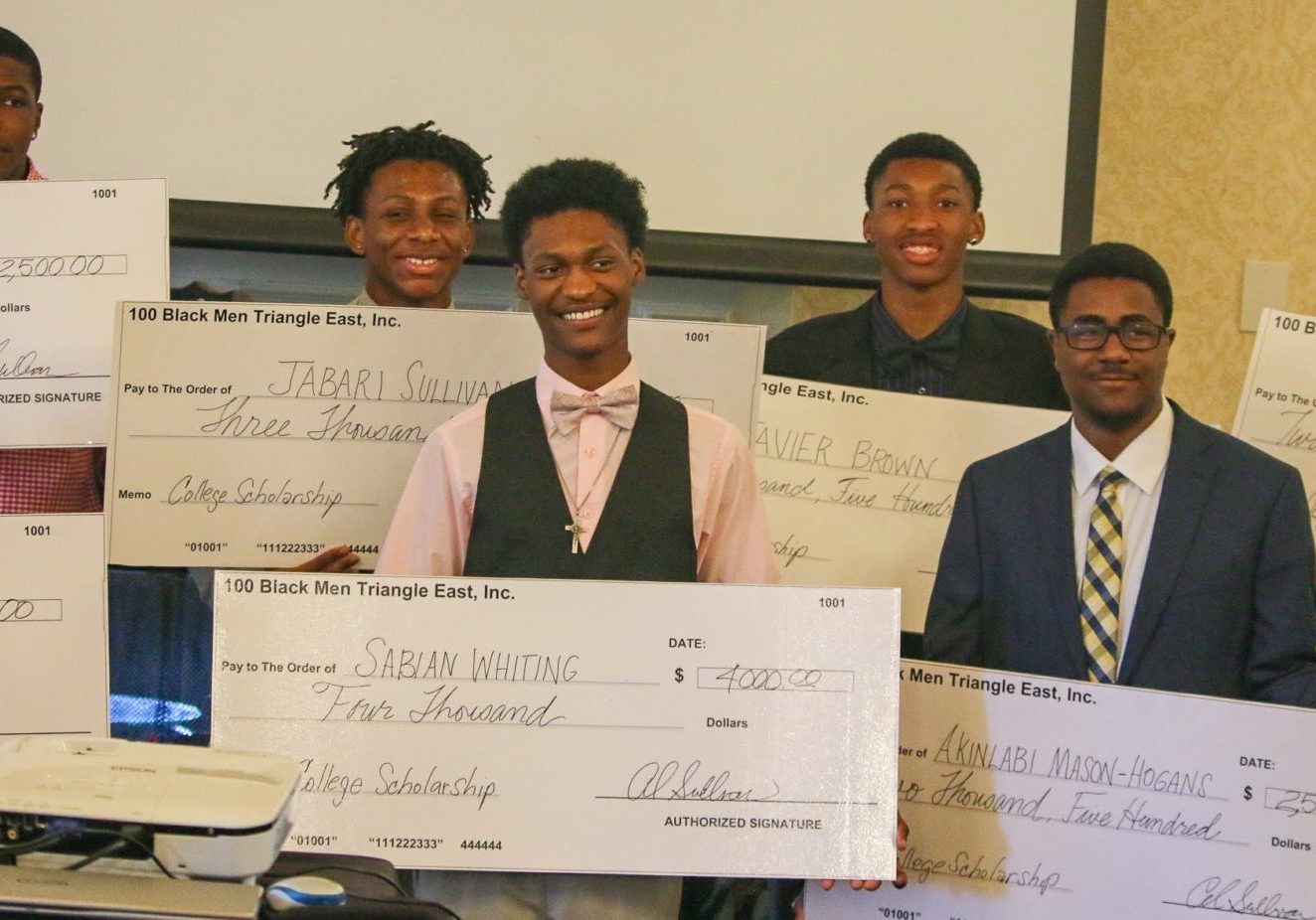 A group of young men holding oversized checks